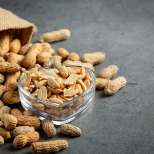 Groundnuts in heart shape plate put next to  a sack of groundnuts