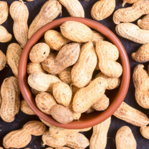 Macro shots of peanuts in bowl on stone background .