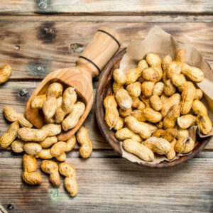 Peanuts in a bowl and a wooden scoop. On a Wooden background.